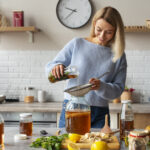 mujer preparando jugos medicinales en cocina con ingredientes naturales como jengibre, limón y frutas