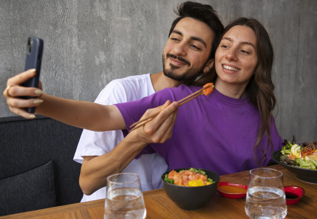 Pareja joven compartiendo comida y tomando una selfie, ejemplo de amor inteligente y momentos felices en pareja.