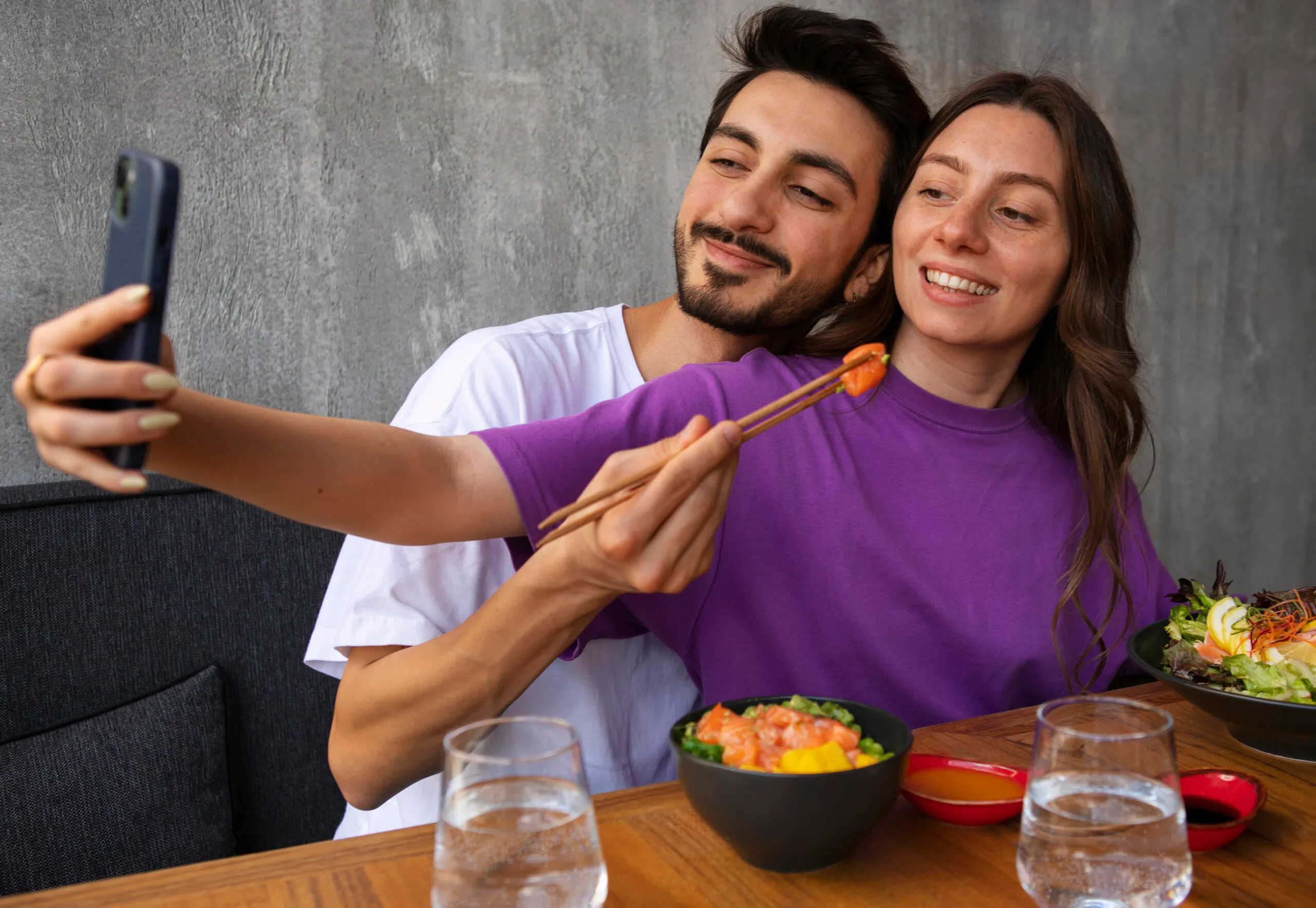 Pareja joven compartiendo comida y tomando una selfie, ejemplo de amor inteligente y momentos felices en pareja.