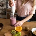 Mujer preparando jugos medicinales caseros con frutas frescas en la cocina