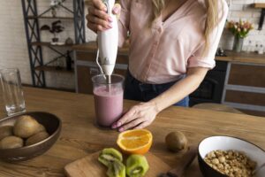 Mujer preparando jugos medicinales caseros con frutas frescas en la cocina