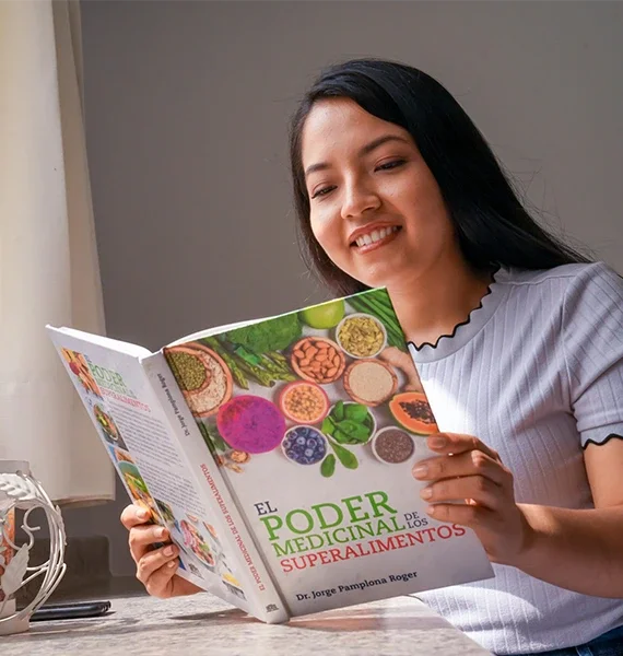 Mujer leyendo el libro El poder medicinal de los superalimentos, fortaleciendo su bienestar y salud familiar mediante la alimentación.