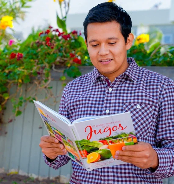 Joven leyendo el libro El poder medicinal de los jugos, promoviendo el bienestar y salud familiar a través de la alimentación.